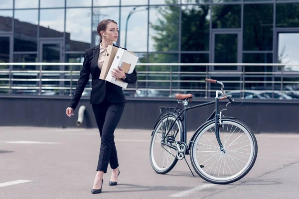 Junge Geschäftsfrau Mit Kopfhörern Und Dokumenten Läuft Mit Abgestelltem Fahrrad — Stockfoto