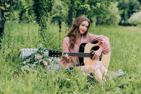 Ung Smilende Kvinde Med Akustisk Guitar Hviler Tæppe Med Buket - Stock-foto