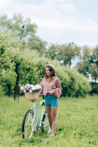 Young smiling woman with retro bicycle with wicker basket full of flowers in forest — Stock Image Young Smiling Woman Retro Bicycle Wicker Basket Full Flowers Forest Royalty Free Stock Images