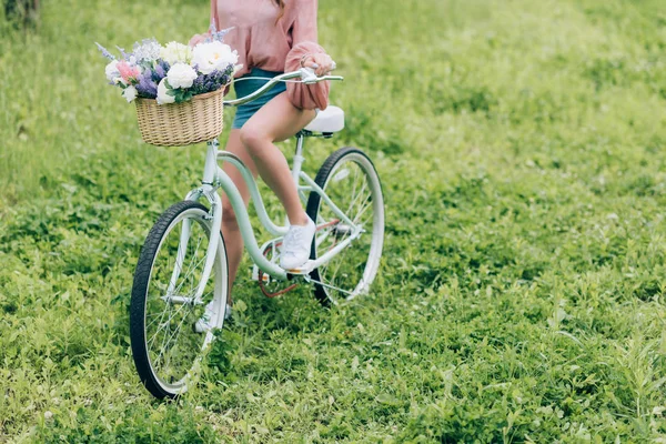 Partial view of woman on retro bicycle with wicker basket full of flowers in forest — Stock Image Partial View Woman Retro Bicycle Wicker Basket Full Flowers Forest Stock Picture