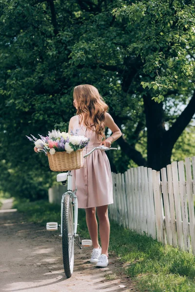 Νεαρή Γυναίκα Στο Φόρεμα Ρετρό Ποδήλατο Ψάθινο Καλάθι Γεμάτο Λουλούδια — Δωρεάν Φωτογραφία