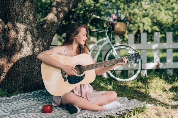 Jovem Atraente Tocando Guitarra Acústica Enquanto Descansa Cobertor Sob Árvore — Fotografia de Stock