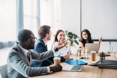 selective focus of multicultural business people having business meeting in office clipart