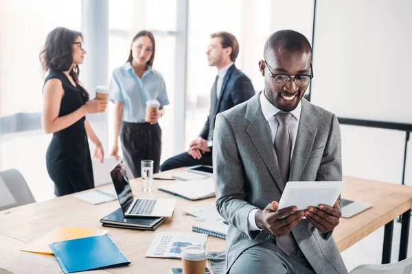 Enfoque Selectivo Sonreír Hombre Negocios Afroamericano Utilizando Tableta Colegas Lugar —  Fotos de Stock