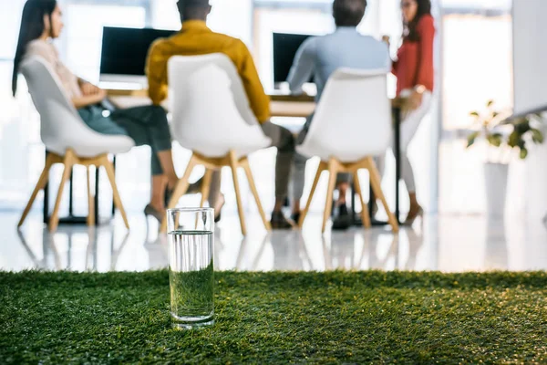 水とオフィスでテーブルに座っている多民族のビジネス人々 のガラスの選択と集中 — ストック写真