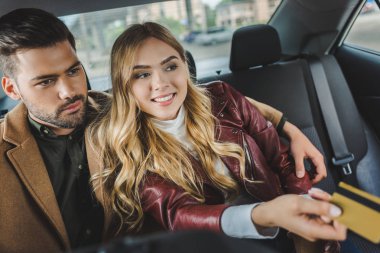 stylish young couple sitting together in taxi, girl holding credit card clipart