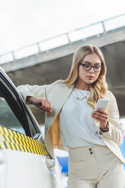 Beautiful Blonde Woman Eyeglasses Leaning Taxi Cab Using Smartphone — Free Stock Photo
