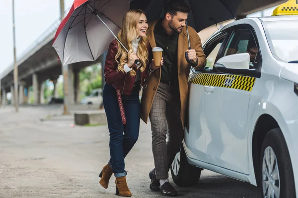 Smiling Young Couple Umbrellas Looking Taxi Car — Stock Photo, Image
