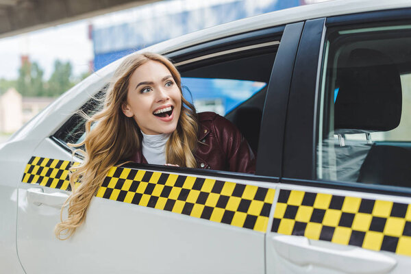 smiling young woman looking away through taxi window  