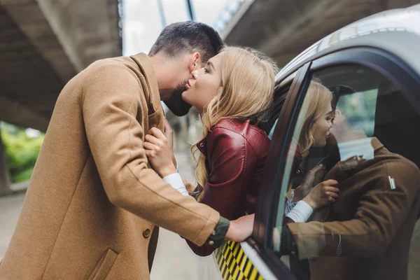 若いカップルがキス 通りに立っている男とタクシーで座っている女の子の側面図 — ストック写真