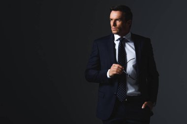 gri arka plan üzerinde izole gözlük tutan ciddi iş adamı 