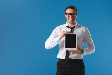 Dijital tablet boş ekran ile tutarak ve mavi izole kamera gülümseyen gözlük yakışıklı adam