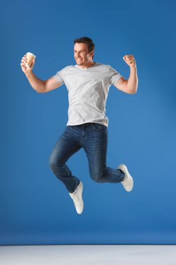 excited man with coffee to go jumping and triumphing on blue clipart