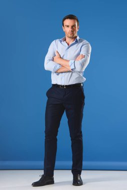 Tam boy görünüm yakışıklı adam ile çapraz kol ayakta ve kameraya mavi arıyor