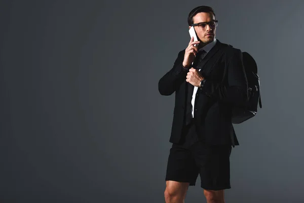 Homem Elegante Confiante Shorts Com Mochila Falando Smartphone Fundo Cinza — Fotografia de Stock