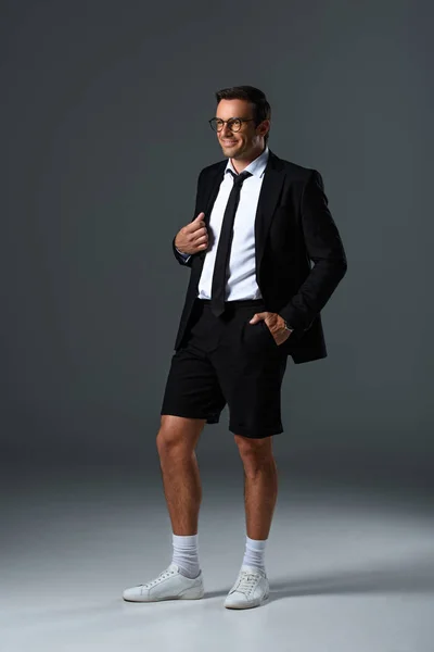 Stylish Man Eyeglasses Shorts Holding Jacket Shoulder Grey Background — Free Stock Photo