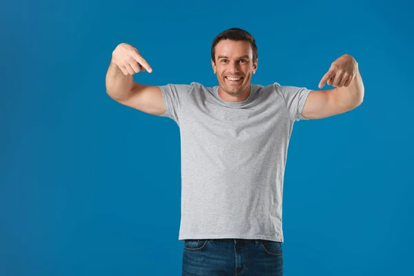 Gelukkig Man Met Vingers Shirt Aan Wijzen Glimlachend Camera Geïsoleerd — Gratis stockfoto