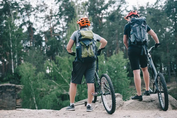 森でマウンテン バイクと立っているヘルメットで男性の極端な自転車の背面図 — ストック写真