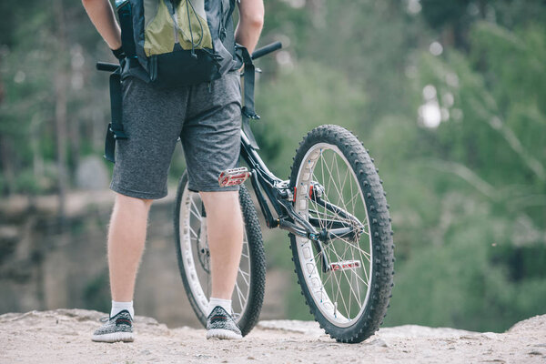 cropped image of male cyclist with backpack standing near bicycle 