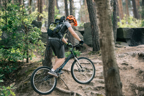 side view of male biker in helmet riding on bmx in forest 