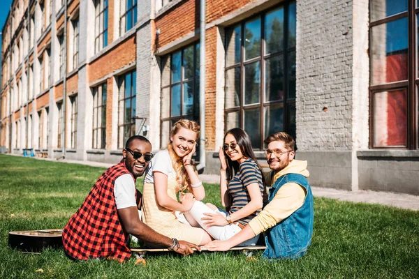 Multiracial Group Friends Looking Camera While Sitting Longboard Green Grass — Free Stock Photo