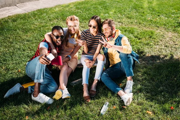 Sorrindo Amigos Multiétnicos Tomando Selfie Smartphone Enquanto Descansam Gramado Verde — Fotos gratuitas