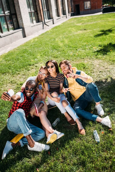 Amigos Multiétnicos Tomando Selfie Smartphone Enquanto Descansam Gramado Verde Juntos — Fotografia de Stock