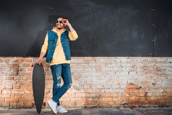 Stilvoller Mann Mit Sonnenbrille Und Longboard Steht Auf Der Straße — Stockfoto