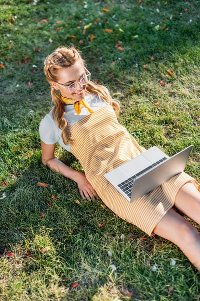 Высокий Угол Обзора Улыбающейся Женщины Ноутбуком Отдыхающей Зеленой Траве Парке — Бесплатное стоковое фото