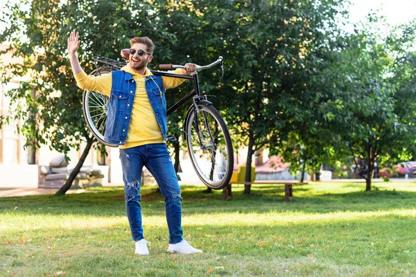 Pemuda Ceria Berkacamata Hitam Dengan Sepeda Retro Menyapa Seseorang Taman — Foto Stok Gratis