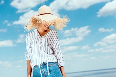 gülümseyen mavi bulutlu gökyüzü karşı hasır şapkalı Afrika kökenli Amerikalı kadın