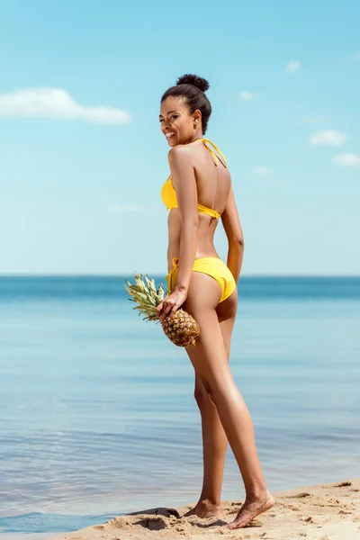 Vista Ángulo Bajo Sonriente Mujer Afroamericana Bikini Sosteniendo Piña Playa —  Fotos de Stock