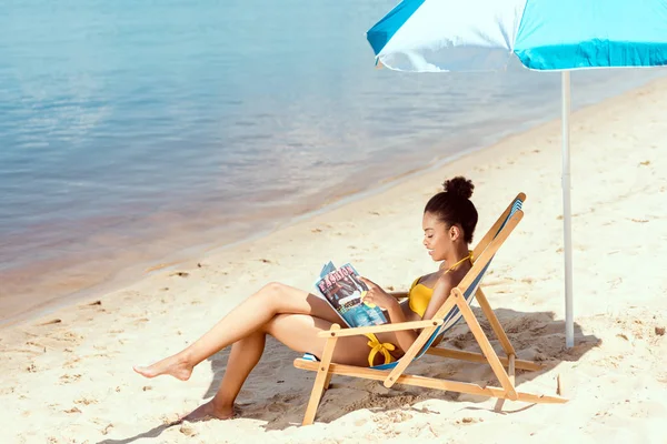 Young African American Woman Reading Magazine Relaxing Deck Chair Beach — Stock Photo, Image