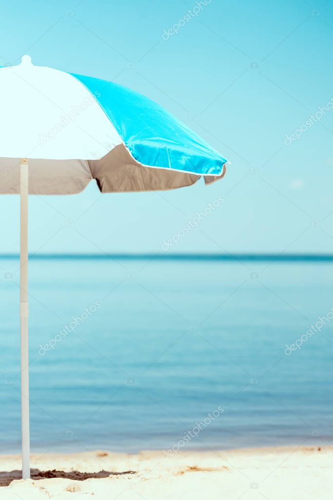 selective focus of beach umbrella in front of sea 