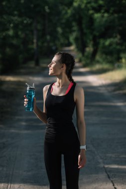 spor şişe su ile parkta tutan atletik kadın