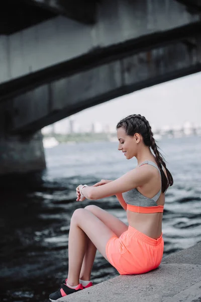 Sportswoman Looking Smart Watch Sitting Quay — Free Stock Photo