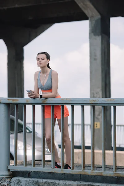 Pensive Sportswoman Earphones Smartphone Standing Railings Bridge — Stock Photo, Image