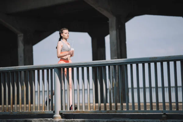 スポーツウーマン ジョギングや市内の橋の上の音楽を聴く — ストック写真