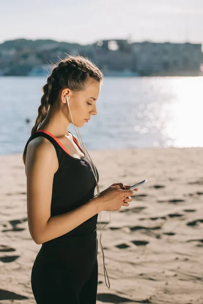 Bela Esportista Ouvir Música Com Fones Ouvido Usando Smartphone Praia — Fotografia de Stock