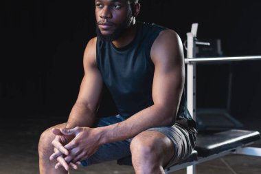 genç Afro-Amerikan sporcu pudrası oturan ve uzağa bakarak elleri ile kadeh kırpılmış