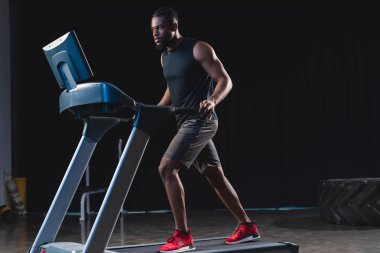 Tam boy görünüm atletik genç Afro-Amerikan adamın koşu bandı üzerinde çalışan