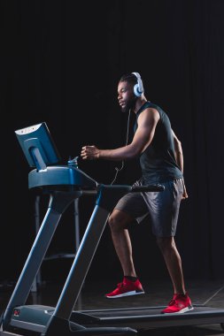 yakışıklı genç Afro-Amerikan sporcu koşu bandı üzerinde çalışan Kulaklığımda yan görünüm