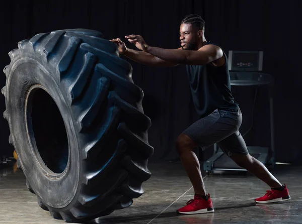 肌肉发达的非洲裔美国运动员与轮胎运动的侧面视图 — 图库照片