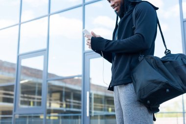 Afro-Amerikan smartphone kullanarak kulaklık erkekte gülen in atış kırpılmış
