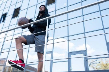 sportif Afro-Amerikan adamın sokakta basketbol topu tutan düşük açılı görünüş