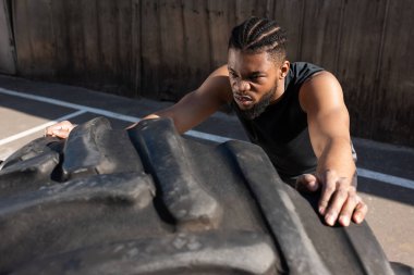 sportif Afro-Amerikan adamın sokakta lastik ile eğitim yüksek açılı görünüş