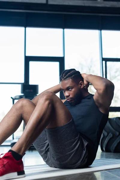 ジムで腹筋をやって若いアフリカ系アメリカ人のスポーツマンを集中 — ストック写真