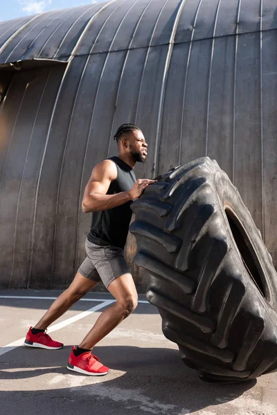 Athletischer Afrikanisch Amerikanischer Mann Trainiert Mit Reifen Auf Der Straße — kostenloses Stockfoto