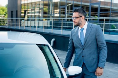 sokakta arabanın kapısını açarak gözlük işadamı