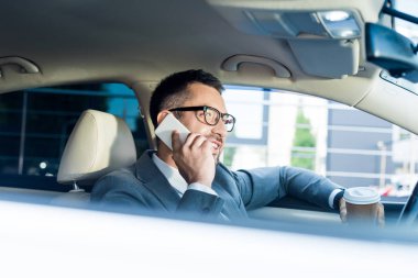 gülümseyen işadamı kahve ile Smartphone cep telefonu ile arabada konuşmaya başladın yan görünüm 